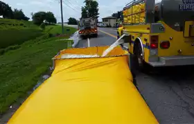 Yellow fire truck dispensing water into a frame tank