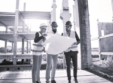 3 workers with helmet looking at a blueprint